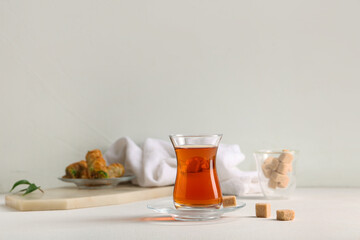 Glass of Turkish tea with sugar cubes on white background