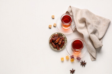 Glasses of Turkish tea with delights, dried dates and anise stars on white background