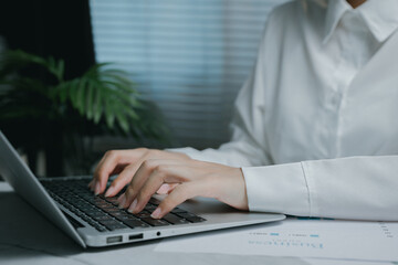 Focused person working on laptop with papers, Business concept