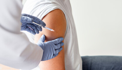 Vaccine or flu shot in injection needle. Doctor working with patient's arm.