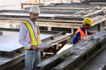 Engininspecting the work that technicians are doing by pouring cement for building components and...