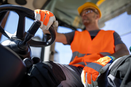 Construction worker driving heavy machinery during daytime work shift in an urban setting