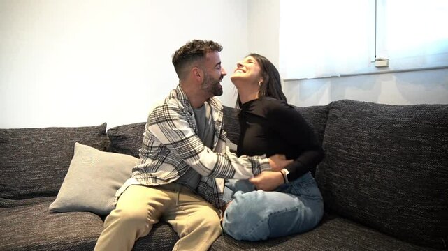 Loving couple embracing, cuddling adorable irish wolfhound on soft living room couch