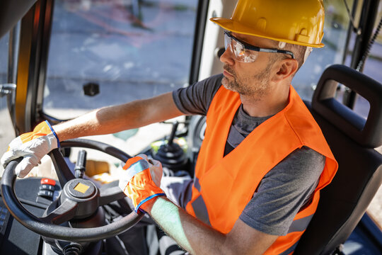 Construction worker operating a heavy machine at a job site during daylight hours