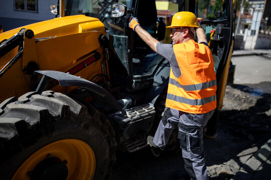 Worker operating construction machinery on urban site during daytime