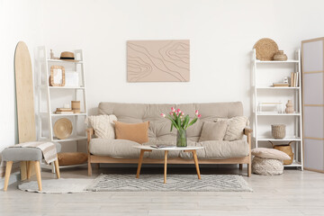 Interior of living room with sofa, shelving units, beautiful tulip flowers and magazines on coffee table