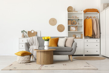 Interior of living room with sofa, wardrobe, beautiful tulip flowers and magazines on coffee table
