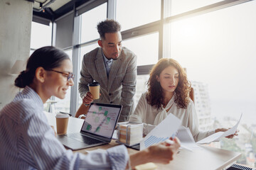 A team gathers together to discuss various work strategies over coffee in a modern, inviting office setting