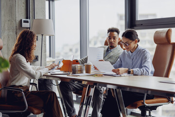 In a sleek, modern office meeting space, a diverse group of enthusiastic and dynamic professionals collaborates