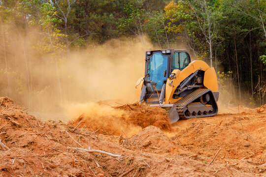 Powerful bulldozer clears soil, debris while dust clouds rise in rural forest setting during preparing land for development - Powered by Adobe