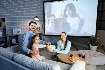Family with popcorn watching movie together at home