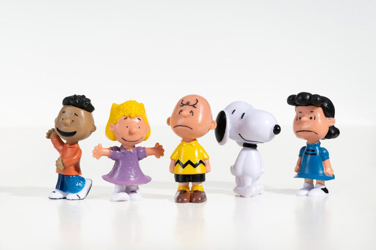 Five Peanuts characters figurines standing in a row on a white background