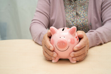 Retired elderly woman counting coins money with piggy bank and worry about monthly expenses and treatment fee payment.