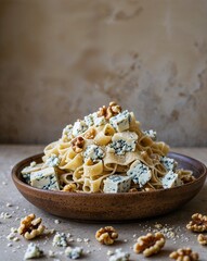 A crumbly looking blue cheese and walnut pasta on a plain rustic beige background