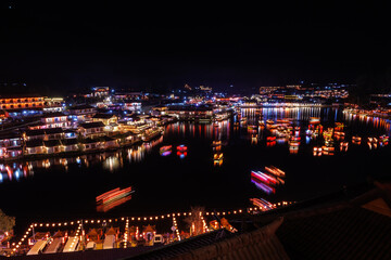 Fototapeta premium Ban Rak Thai Village at night scene, over colorful lighting and beautiful decorative lamps, motion blur chinese boats in the lake,