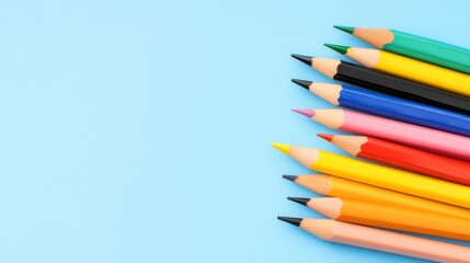 Fototapeta premium Colorful pencils arranged on a light blue background, leaving copy space. The pencils are sharpened and point towards the center.