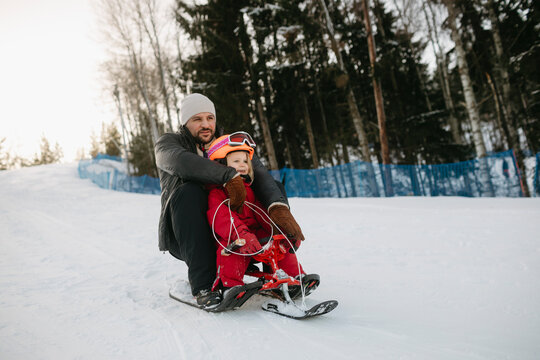 Father and daughter sliding down on sledge at ski resort
