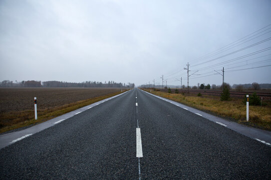 Straight empty road against cloudy sky