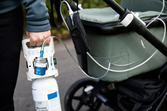 Midsection of person holding oxygen cylinder connected to baby stroller