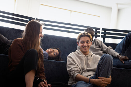 Smiling blond young man spending leisure time with friends at campus