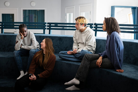Multiracial female and male friends spending leisure time talking with each other at university campus