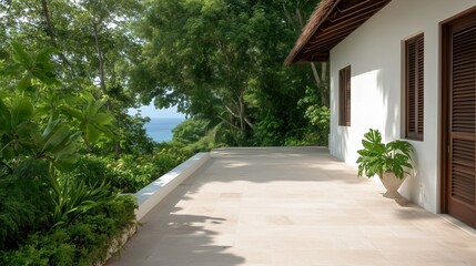 Fototapeta premium A serene outdoor terrace with lush greenery and a partial view of the ocean, adjacent to a modern building