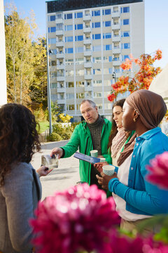 Male volunteer giving pamphlet to neighbors in public park
