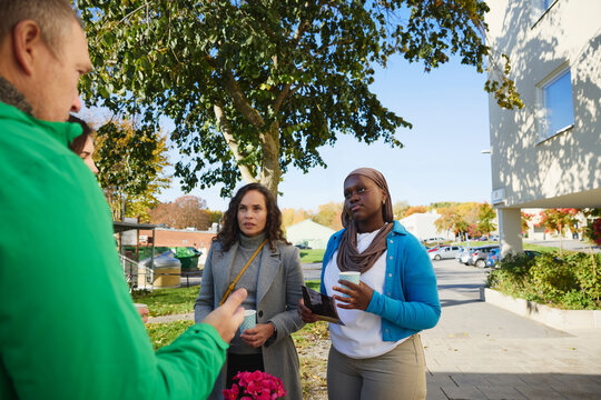 Female neighbors listening to male volunteer explaining about charity work at park