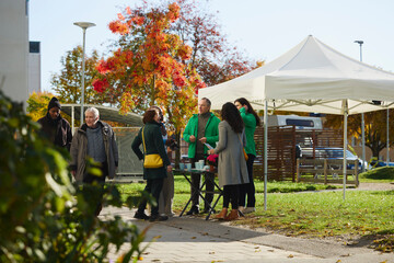 Male friends talking with each other while group of people having discussion over charity work at park