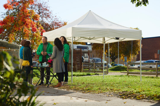 Multiracial female neighbors discussing over charitable meet with volunteers at public park
