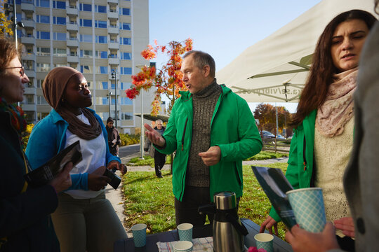 Mature male volunteer talking with woman wearing headscarf in park