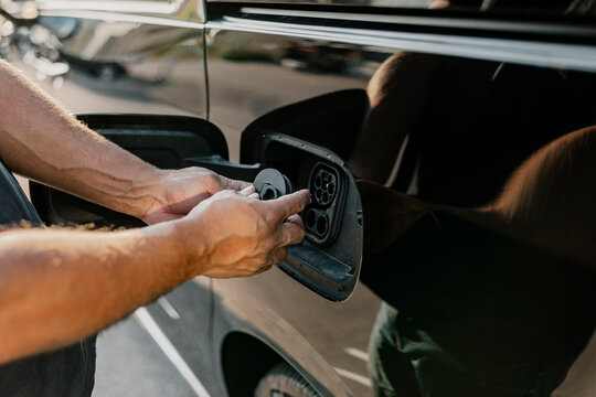 Hand of man closing charging outlet of electric car