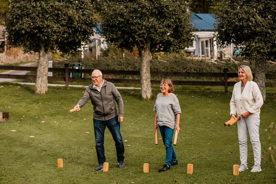 Happy male and female senior friends playing Molly game in back yard