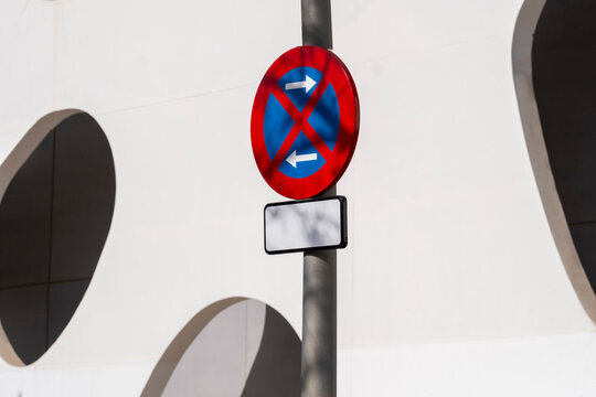 No parking sign mounted on modern facade with circular patterns, urban design element and traffic signal detail for architecture, transport and public space visuals