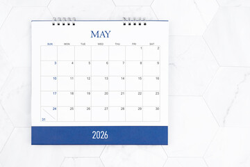 May 2026 desk calendar on white marble tiles background.