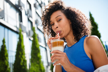 Young afro american woman enjoying coffee outdoors in urban setting