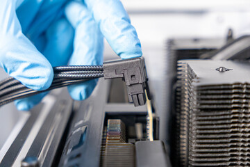 Technician in blue gloves positioning angled 16-pin PCIe power cable near graphics card socket...