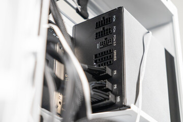 Close-up of modular power supply unit with labeled ports and connected black power cables inside...