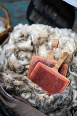 Raw wool with wooden carding brushes on a rustic surface
