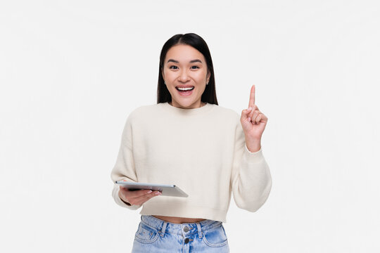 Smiling Asian woman girl student holding using tabled pad for remote work, e-learning at university college, e-banking, online shopping pointing finger up isolated over white background
