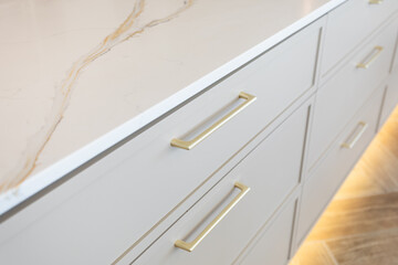Gold handles on light grey drawers with a white marbled counter top. Kitchen remodel. Kitchen cabinetry.