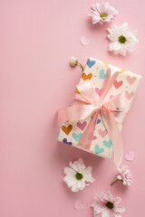 Gift box wrapped in heart-patterned vertical paper with a ribbon, surrounded by white flowers