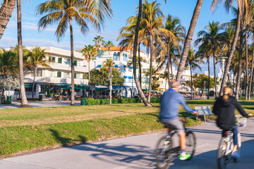 A vibrant street scene in Miami Beach with palm trees, colorful Art Deco-style buildings, and...