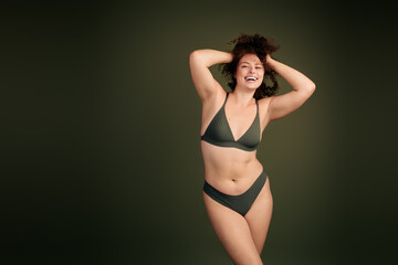Fototapeta premium Confident young woman in khaki underwear posing against plain background showcasing natural beauty and self acceptance
