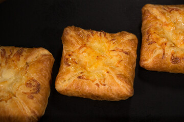 Puff pastry with cheese on a black background, top view