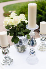 White roses and pillar candles on elegant silver holders