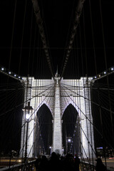 Obraz premium brooklyn bridge detail at night (manhattan east river crossing in the dark) illuminated historic landmark monument new york city icon (iconic suspension structure) tourism nightlife travel destination