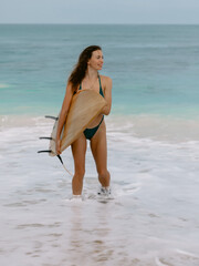 Surfer girl with surfboard on beach goes to surfing. Woman in sexy bikini