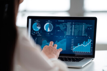 Close-up of a woman's hands working with a laptop displaying graphics and information.