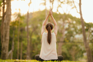 Young Asian woman practicing yoga in a quiet park, gracefully in a relaxed pose, relaxing and...